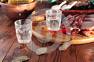 Traditional drink vodka in glasses, with a snack in the form of cold cuts and bacon, cucumbers, preservation. Russian festive