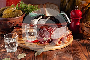 Traditional drink vodka in glasses, with a snack in the form of cold cuts and bacon, cucumbers, preservation. Russian festive