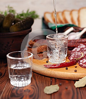 Traditional drink vodka in glasses, with a snack in the form of cold cuts and bacon, cucumbers, preservation. Russian festive