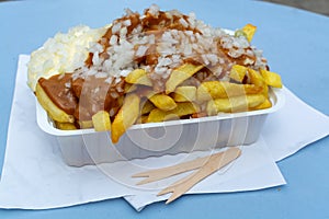 Traditional Dutch fast food dish, fried potatoes with sate sauce, onion and mayonaise, fat and not healthy street food