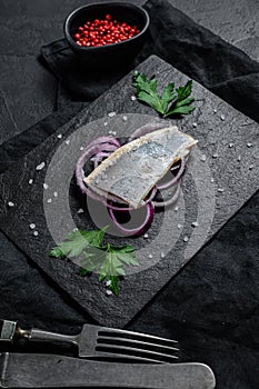 Traditional Dutch food herring with red onion. New season of herring called Hollandse nieuwe. Black background. Top view