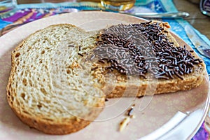 Traditional Dutch hagelslag chocolate sugar sprinkles on whole wheat slice of bread with peanut butter, considered a breakfast