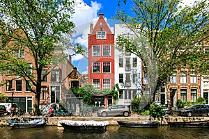 Traditional dutch houses and boats on canal in the most romantic city. Tranquil scene of Amsterdam street in summer. Netherlands.