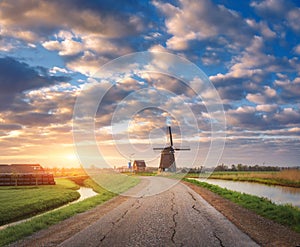 Traditional dutch windmill against colorful sky with clouds