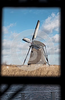 Traditional dutch windmill near the canal. Netherlands. Old windmill stands on the banks of the canal, and water pumps. White clou