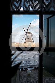 Traditional dutch windmill near the canal. Netherlands. Old windmill stands on the banks of the canal, and water pumps. White clou