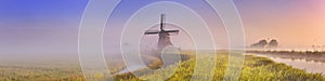 Traditional Dutch windmill at sunrise on a foggy morning