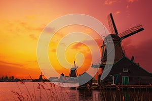 Traditional Dutch windmills on the canal bank at warm sunset light in Netherlands