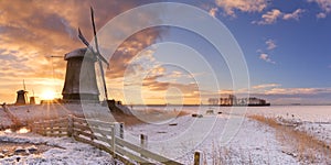 Traditional Dutch windmills in winter at sunrise photo