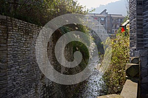 Traditional dwelling building by weedy riverside in small town