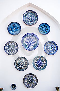 traditional east Uzbek ceramic plates hand-painted on wall at oriental tableware shop in Uzbekistan