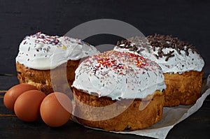 Traditional Easter bread or cake with white glaze decorated with multicolored rainbow sprinkle on the black wooden background