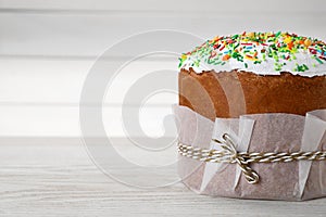 Traditional Easter cake with sprinkles on white wooden table, closeup. Space for text