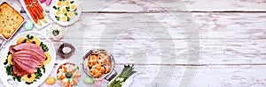Traditional Easter ham dinner. Overhead view corner border on a white wood banner background with copy space.