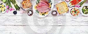 Traditional Easter ham dinner. Overhead view top border on a white wood banner background with copy space.