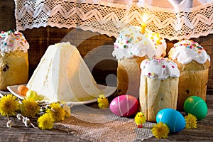 The traditional Easter treats: cakes and colorful easter eggs on a table in a rustic style.