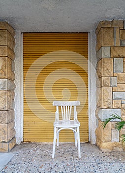 Traditional Egyptian white wooden chair over in front of bricks stone wall and yellow roll-up door