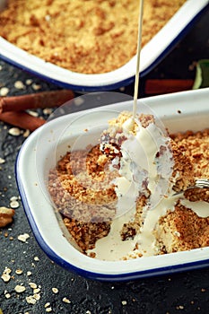 Traditional English apple crumble baked in vintage dish and served with cream