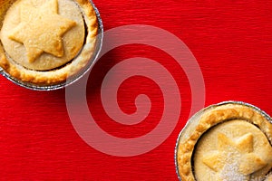 Traditional English Christmas dessert pastry mince pies in muffin tins sprinkled with sugar on crimson red velveteen