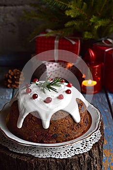 Traditional english Christmas steamed pudding with winter berries, dried fruits, nut in festive setting with Xmas tree and burning