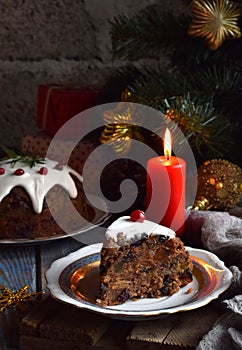 Traditional english Christmas steamed pudding with winter berries, dried fruits, nut in festive setting with Xmas tree and burning