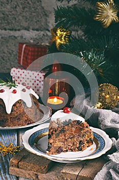 Traditional english Christmas steamed pudding with winter berries, dried fruits, nut in festive setting with Xmas tree and burning