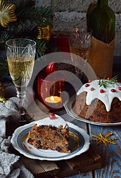 Traditional english Christmas steamed pudding with winter berries, dried fruits, nut in festive setting with Xmas tree, burning ca