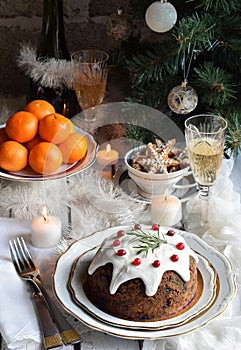 Traditional english Christmas steamed pudding with winter berries, dried fruits, nut in festive setting with Xmas tree, burning ca