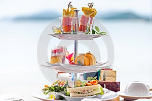 Traditional english high tea stand with selection of sweets, cakes, sandwiches