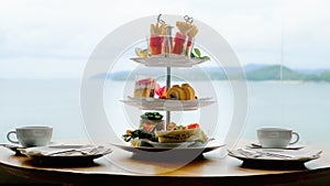 Traditional english high tea stand with selection of sweets, cakes, sandwiches