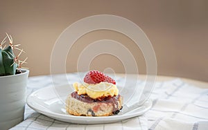 Traditional English Scones with strawberry jam and clotted cream topped with fresh strawberry