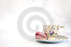 traditional English tea, high tea with vintage porcelain tea cup and pink macarone on white background, copy space