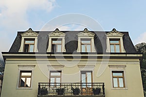 Traditional European Balcony with colorful flowers and flowerpots. Pattern building yellow with wood windows and classic style in