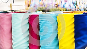 Traditional fabric store with stacks of colorful textiles, fabric rolls at market stall - textile industry background with blurred