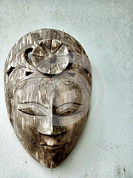 A traditional face mask made of carved wood typical of Indonesian Java on a wall of a house