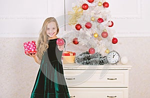 Traditional family holiday. Kid girl near christmas tree hold gift box. Child celebrate christmas at home. Favorite day