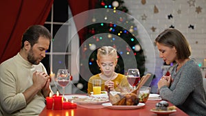 Traditional family praying before having Xmas dinner, belief in god Christianity