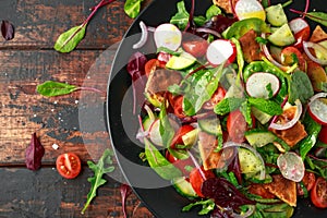 Traditional fattoush salad on a plate with pita croutons, cucumber, tomato, red onion, vegetables mix and herbs