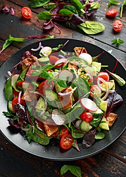 Traditional fattoush salad on a plate with pita croutons, cucumber, tomato, red onion, vegetables mix and herbs