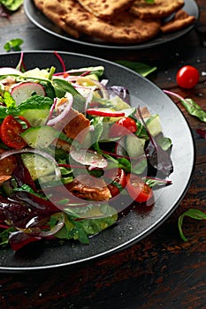 Traditional fattoush salad on a plate with pita croutons, cucumber, tomato, red onion, vegetables mix and herbs