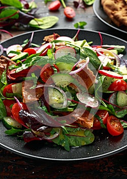 Traditional fattoush salad on a plate with pita croutons, cucumber, tomato, red onion, vegetables mix and herbs