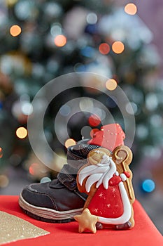 Traditional festive holiday boots filled with treats and Saint Nicholas cookies on bokeh background. Classical holiday