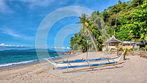 A wooden outrigger boat on a tropical island beach in the Philippines.