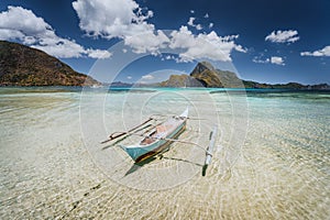 Traditional filippino fishermen banca boat in blue tropical lagoon at El Nido bay with Cadlao Island on Background