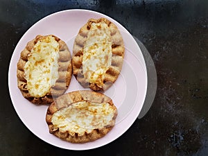 Traditional Finnish Karelian pies on a plate with black background.