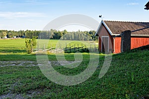 Traditional Finnish red wooden barn with roundpole fence