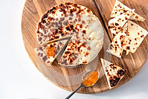 Traditional finnish squeaky cheese with cloudberry jam on wooden cutting board.