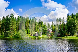 A traditional Finnish wooden cottage with a sauna and a barn on the lake shore. Summer rural Finland.