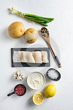 Traditional fish and chips ingredients recipe raw cod fillets on stone slate batter, potatoe, tartar sauce, minty mushy peas,