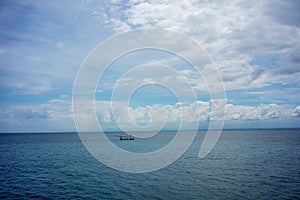 Traditional fisherboat sailing on water with cloudy sky